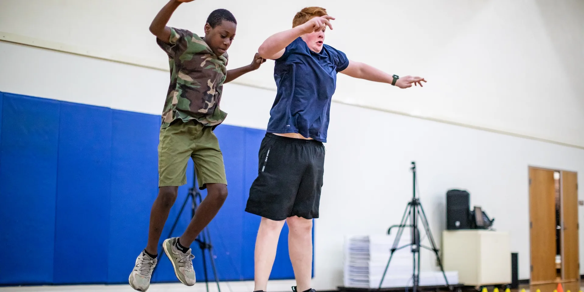 Two young boys jumping in the air in a school gym