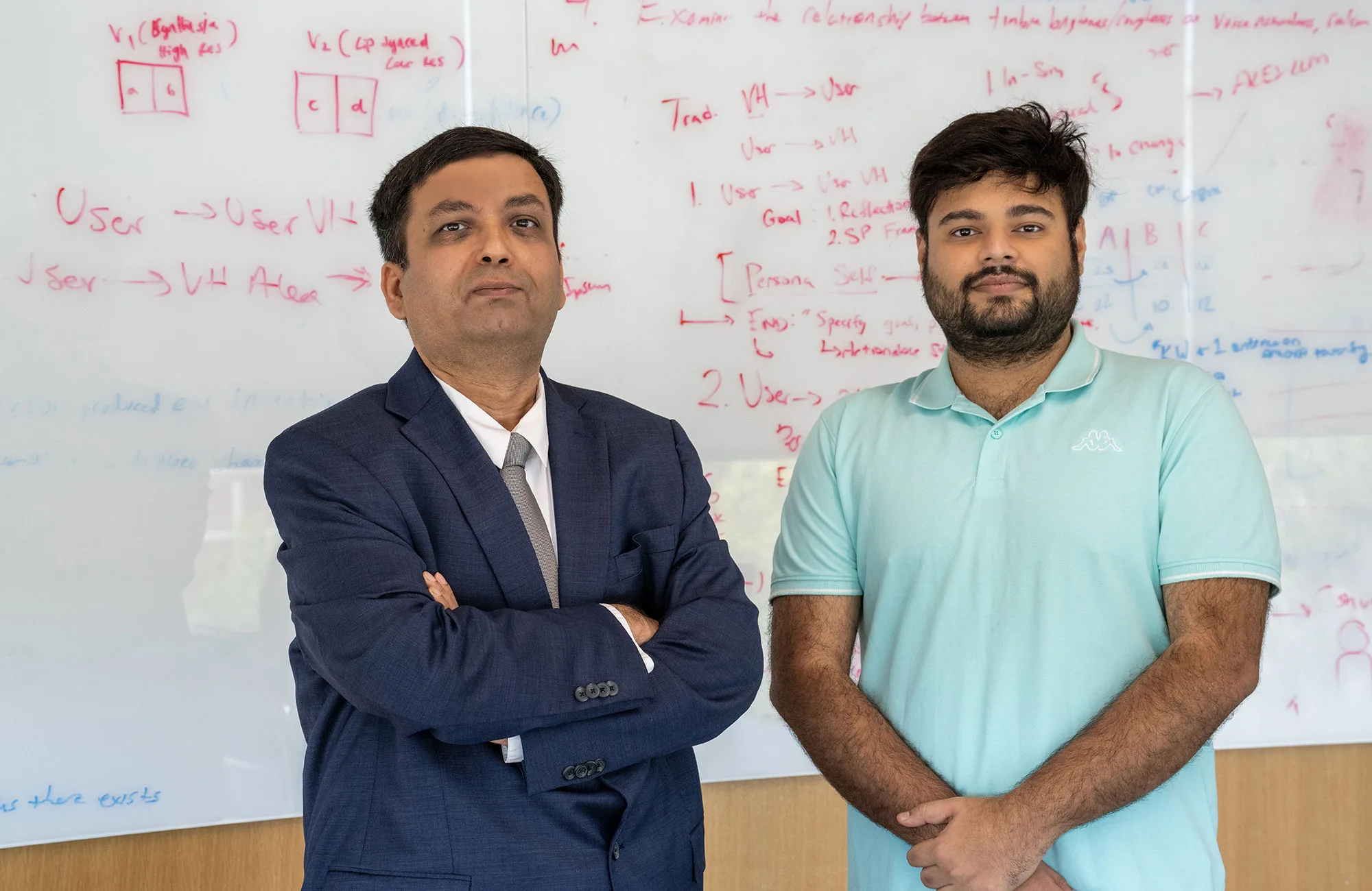 Two men stand side-by-side in front of a whiteboard covered in handwritten notes and diagrams.